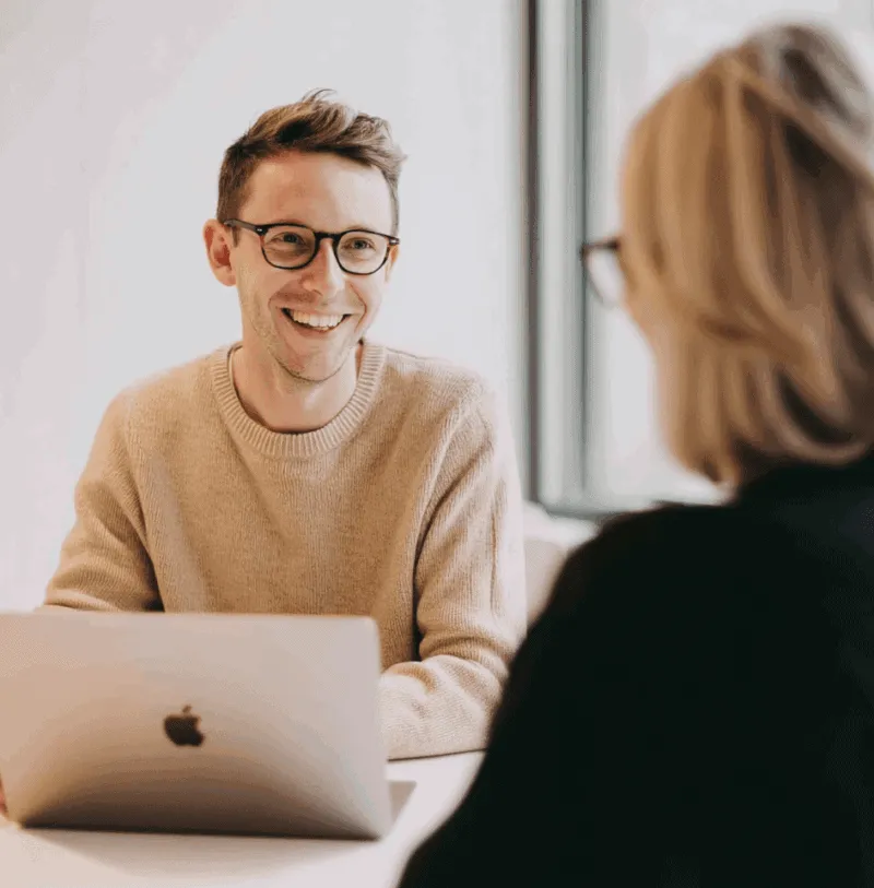 DAM-and-PIM-Customer-Service-1 Smilende kundeservicemedarbejder arbejder på bærbar computer under møde — Digital Asset Management (DAM) og Product Information Management (PIM) løsninger fra Kontainer.