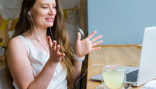 Woman attending online meeting on her laptop smiling and talking with gesturing hands