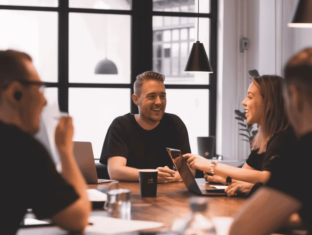 DAM-and-PIM-Customer-Service-3 (1) Teammøde med smilende kolleger, der samarbejder om digitale løsninger — Kontainer Digital Asset Management (DAM) og Product Information Management (PIM).