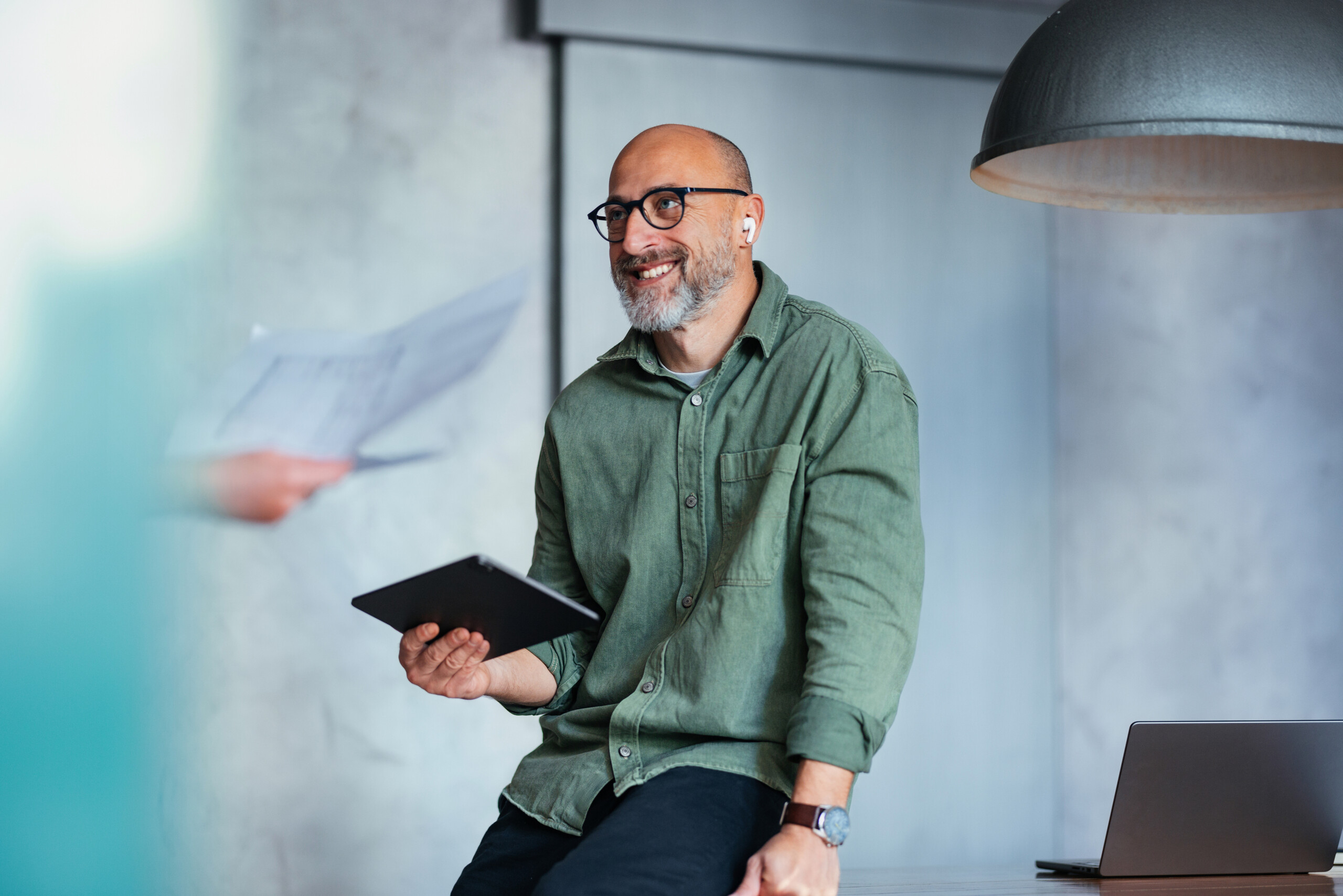 Smiling Businessman Holding a Tablet in a Modern Office Setting
