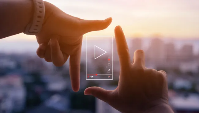 Hands holding a vertical video frame against a blurred sunset sky