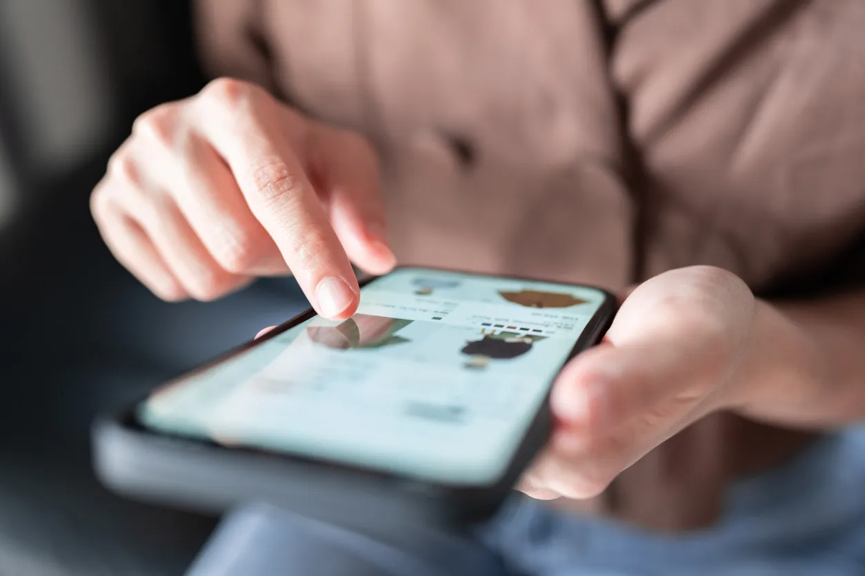 Kvinde der shopper tøj online på sin smartphone derhjemme